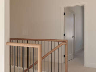 This modern staircase features a sleek design with light wood handrails and black metal spindles, creating an elegant transition between floors.