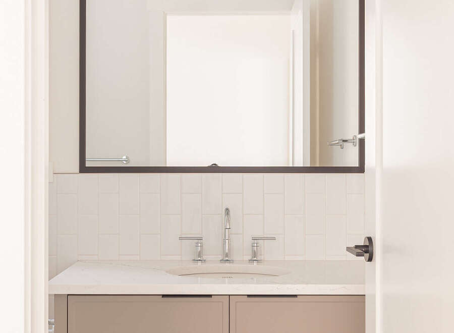 This modern bathroom features a sleek vanity with taupe cabinetry and a white quartz countertop.