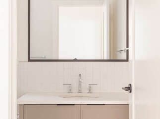 This modern bathroom features a sleek vanity with taupe cabinetry and a white quartz countertop.