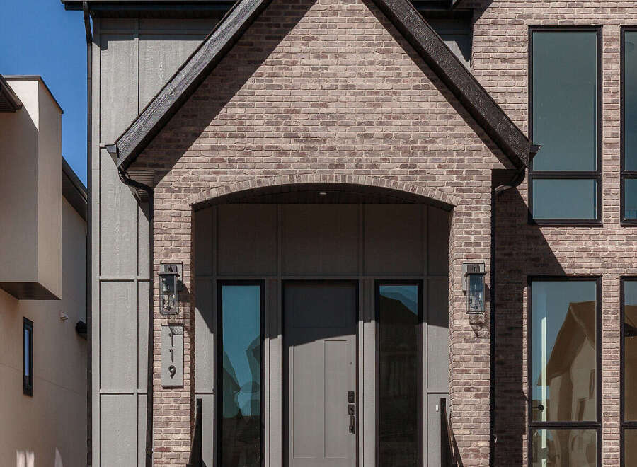 This modern home features a striking facade with a combination of brick and vertical siding.