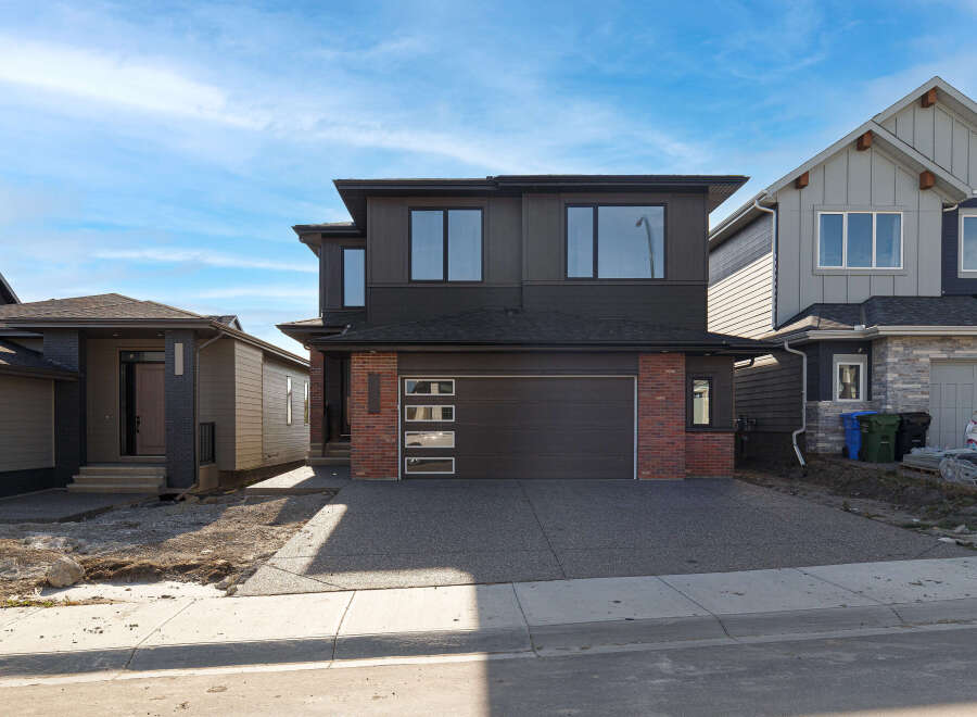 Discover modern living in this stunning two-story home featuring a sleek dark exterior with contrasting brick accents.