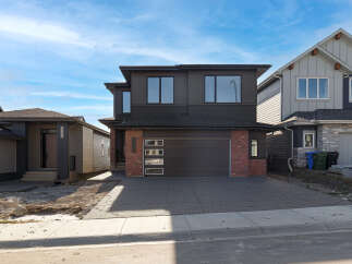 Discover modern living in this stunning two-story home featuring a sleek dark exterior with contrasting brick accents.