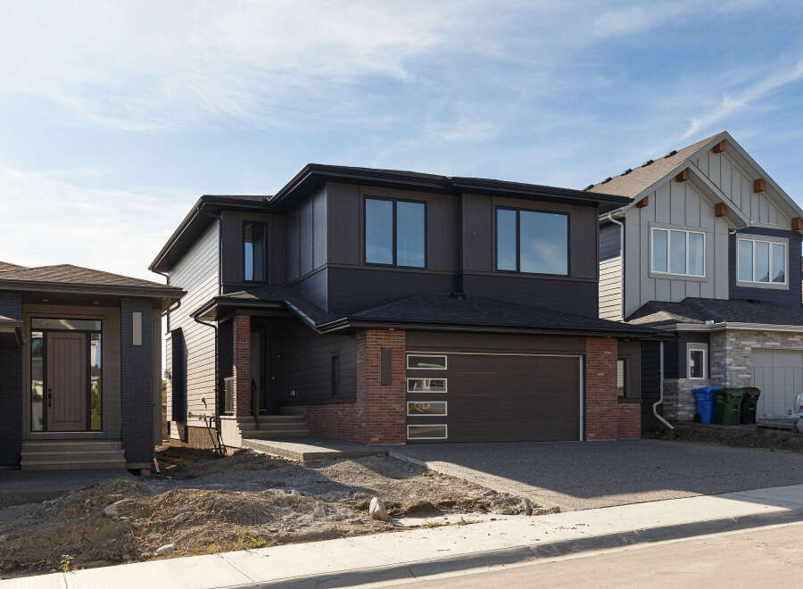 Discover modern living in this stunning two-story home featuring a sleek dark exterior with contrasting brick accents.