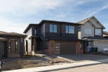 Discover modern living in this stunning two-story home featuring a sleek dark exterior with contrasting brick accents.