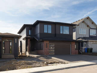 Discover modern living in this stunning two-story home featuring a sleek dark exterior with contrasting brick accents.