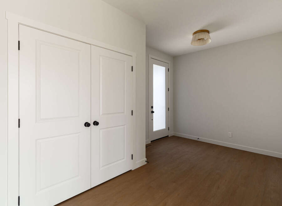 Step into this inviting space featuring a pair of elegant white double doors with classic black hardware, perfect for a closet or room entrance.