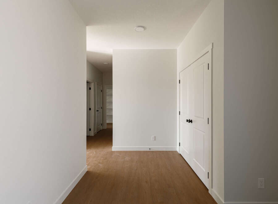 Step into this beautifully appointed hallway, featuring pristine white walls and elegant white doors with modern black hardware.