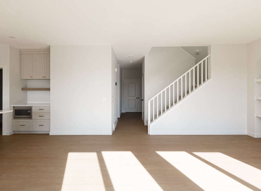 Step into this bright and airy open-concept living space, featuring a modern kitchen with sleek cabinetry and a built-in microwave.