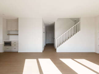 Step into this bright and airy open-concept living space, featuring a modern kitchen with sleek cabinetry and a built-in microwave.