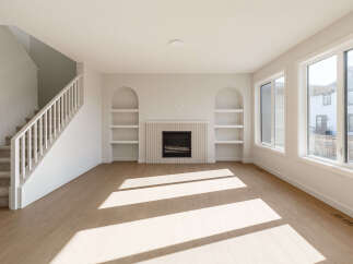 Step into this bright and airy living space, featuring a modern fireplace with a decorative tiled surround and built-in arched shelving.
