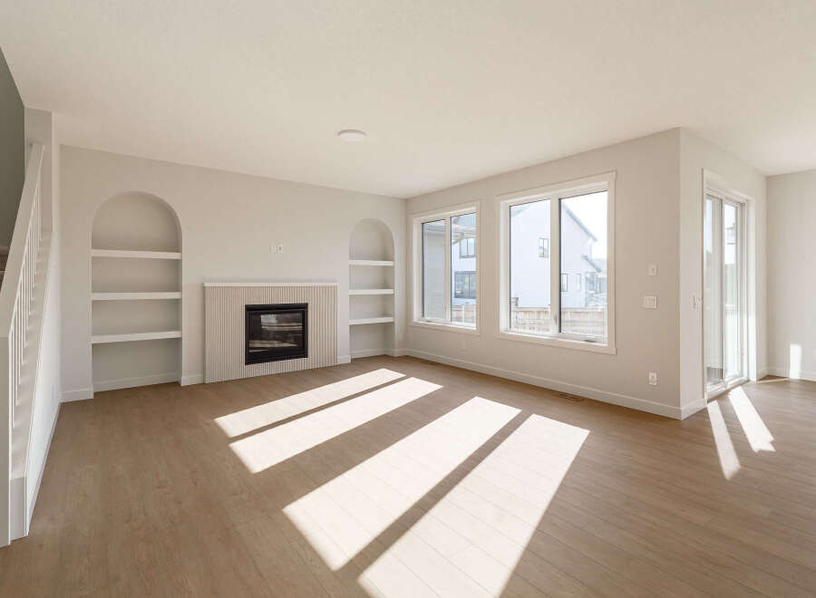Step into this bright and airy living room, featuring a modern fireplace with decorative fluting and built-in arched shelving.