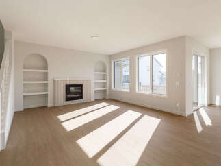 Step into this bright and airy living room, featuring a modern fireplace with decorative fluting and built-in arched shelving.