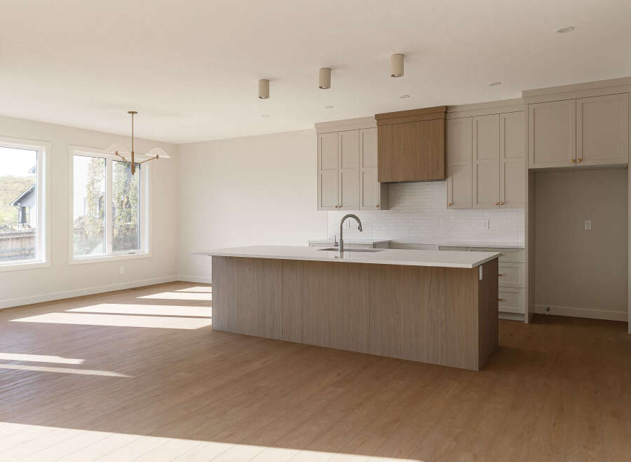 Experience modern living in this spacious kitchen featuring a large island with a waterfall countertop, perfect for meal prep and entertaining.