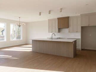 Experience modern living in this spacious kitchen featuring a large island with a waterfall countertop, perfect for meal prep and entertaining.