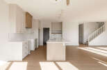 Experience modern living in this spacious open-concept kitchen, featuring sleek white cabinetry, a striking wood-accent island with a waterfall countertop, and a subway tile backsplash.
