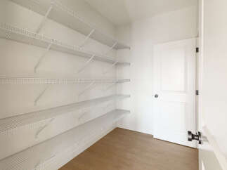 This spacious walk-in pantry offers ample storage with multiple rows of white wire shelving, perfect for organizing groceries and kitchen essentials.