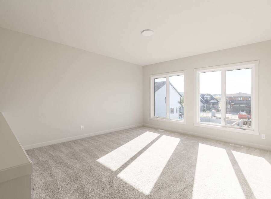 This spacious room features plush, neutral carpeting that complements the light-colored walls, creating a bright and airy atmosphere.