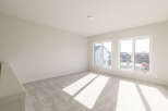 This spacious room features plush, neutral carpeting that complements the light-colored walls, creating a bright and airy atmosphere.
