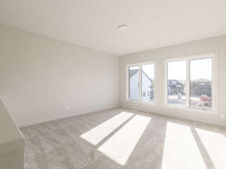 This spacious room features plush, neutral carpeting that complements the light-colored walls, creating a bright and airy atmosphere.