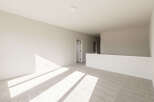 Sunlight streams across the plush carpet of this spacious loft area, highlighting the neutral tones and clean lines.