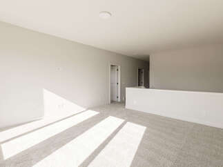 Sunlight streams across the plush carpet of this spacious loft area, highlighting the neutral tones and clean lines.