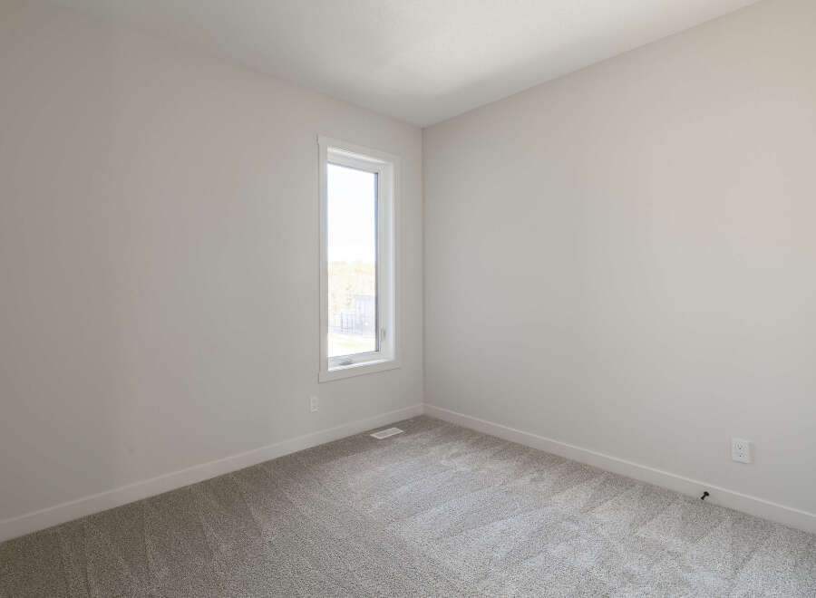 Discover this bright and airy bedroom, featuring a large, vertical window that floods the space with natural light.