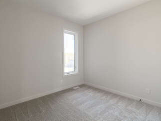 Discover this bright and airy bedroom, featuring a large, vertical window that floods the space with natural light.