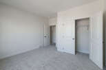 This spacious bedroom features plush, neutral carpeting that complements the clean, white walls.