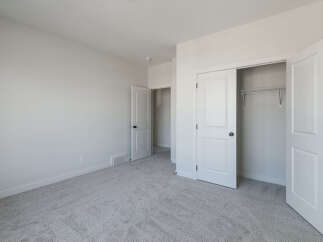This spacious bedroom features plush, neutral carpeting that complements the clean, white walls.