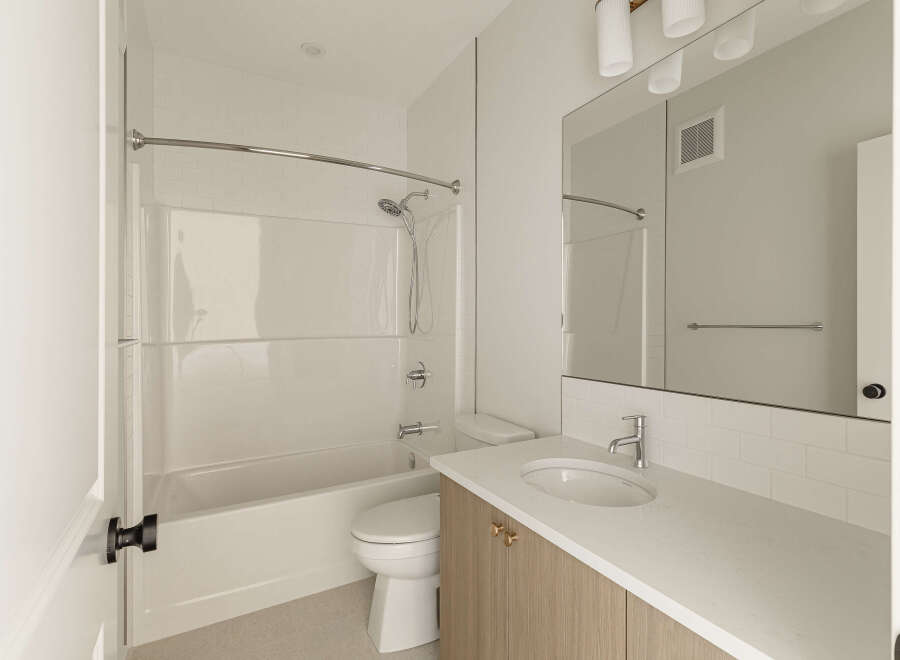 This modern bathroom features a clean white bathtub and shower combination, complemented by sleek chrome fixtures.