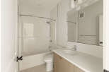 This modern bathroom features a clean white bathtub and shower combination, complemented by sleek chrome fixtures.