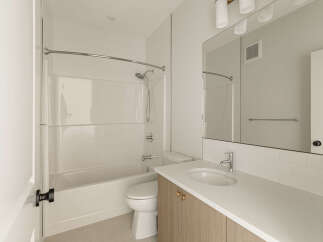 This modern bathroom features a clean white bathtub and shower combination, complemented by sleek chrome fixtures.