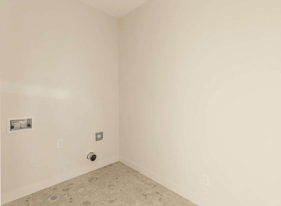 This laundry room is ready for your appliances, featuring a dedicated water hookup box with shut-off valves and a dryer vent.