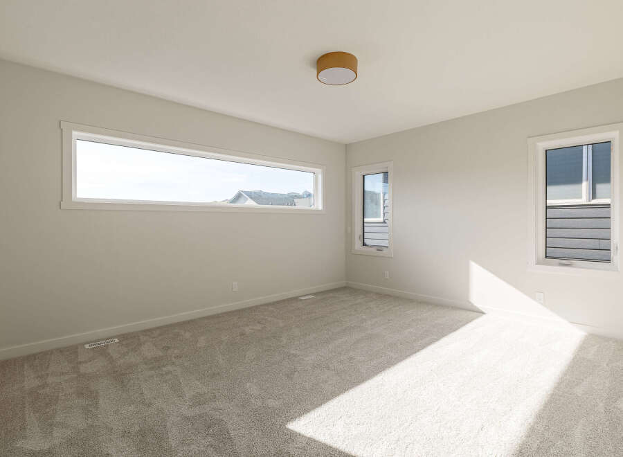 Discover this bright and airy bedroom, featuring a large horizontal window that floods the space with natural light.