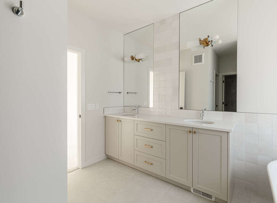 This modern bathroom features a spacious double vanity with a white quartz countertop and light grey cabinetry.
