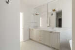 This modern bathroom features a spacious double vanity with a white quartz countertop and light grey cabinetry.