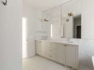 This modern bathroom features a spacious double vanity with a white quartz countertop and light grey cabinetry.