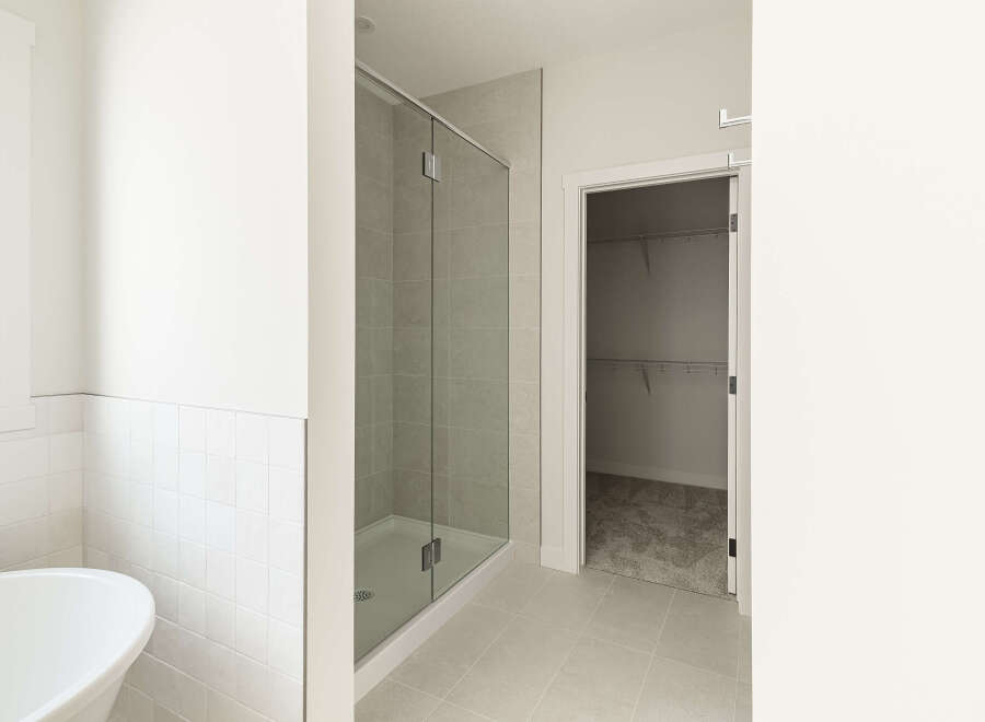 Experience modern luxury in this spacious bathroom, featuring a sleek glass-enclosed shower and a deep soaking tub perfect for relaxation.