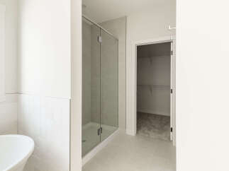 Experience modern luxury in this spacious bathroom, featuring a sleek glass-enclosed shower and a deep soaking tub perfect for relaxation.