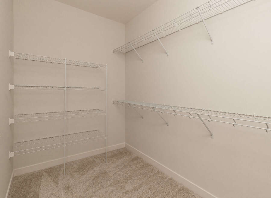 This spacious walk-in closet features ample white wire shelving installed on multiple walls, offering extensive storage solutions.