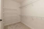 This spacious walk-in closet features ample white wire shelving installed on multiple walls, offering extensive storage solutions.