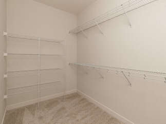 This spacious walk-in closet features ample white wire shelving installed on multiple walls, offering extensive storage solutions.