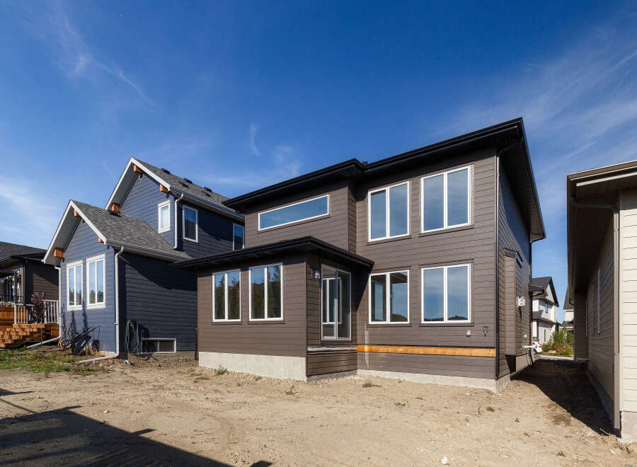 Discover modern living in this stunning new construction home, featuring a sleek dark brown exterior with large, reflective windows that maximize natural light.