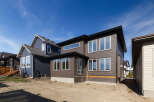 Discover modern living in this stunning new construction home, featuring a sleek dark brown exterior with large, reflective windows that maximize natural light.