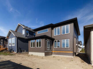 Discover modern living in this stunning new construction home, featuring a sleek dark brown exterior with large, reflective windows that maximize natural light.