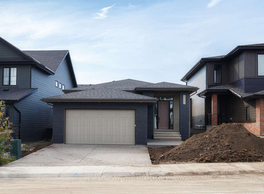 Discover modern living in this stunning new construction home, featuring a sleek dark exterior with contrasting brick accents and a spacious attached garage.