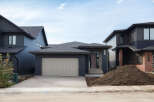 Discover modern living in this stunning new construction home, featuring a sleek dark exterior with contrasting brick accents and a spacious attached garage.