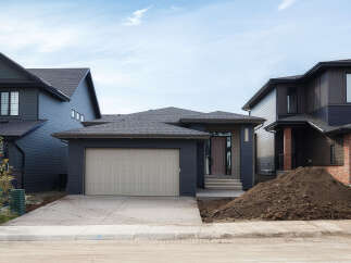 Discover modern living in this stunning new construction home, featuring a sleek dark exterior with contrasting brick accents and a spacious attached garage.