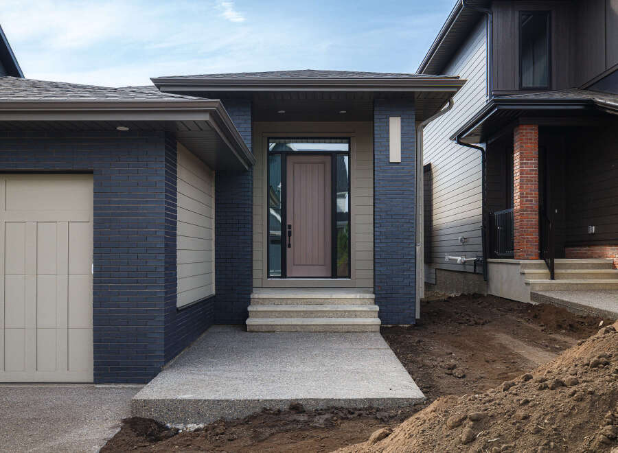 Discover modern living in this stunning new construction home, featuring a striking facade with dark blue brick and complementary siding.