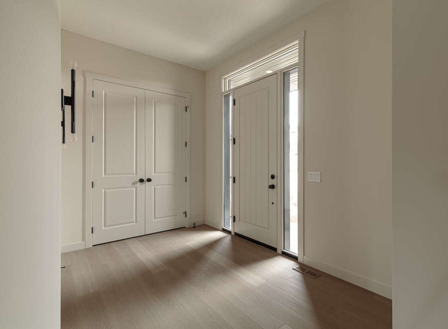 Step into a bright and airy entryway featuring a modern black wall sconce and elegant double doors.